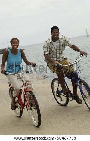 Couple cycling on beach, smiling