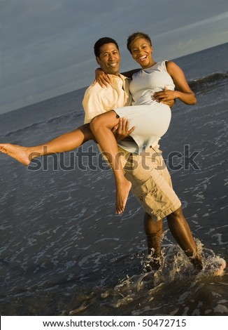 Man carrying woman at ocean, (portrait)