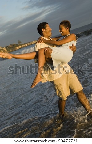 Man carrying woman at ocean
