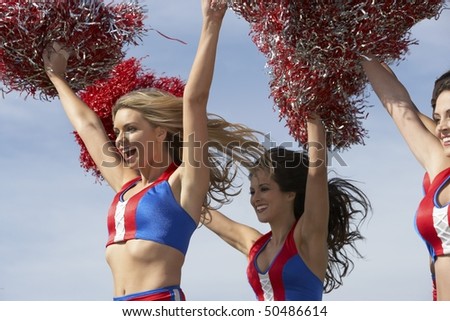 Cheerleaders running holding pom poms in air