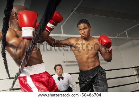 Boxers fighting in ring with referee watching