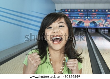 Young woman at bowling alley celebrating, portrait