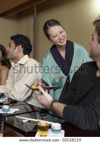 Waitress serving sushi to restaurant