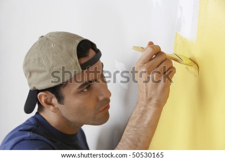Man carefully painting interior wall, close-up