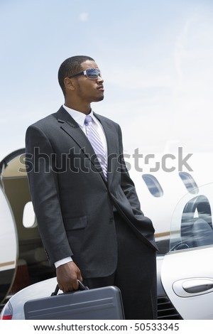 stock-photo-businessman-standing-beside-airplane-hand-in-pocket-holding-a-briefcase-50533345.jpg