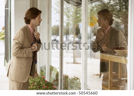 Businessman adjusting tie in shop window