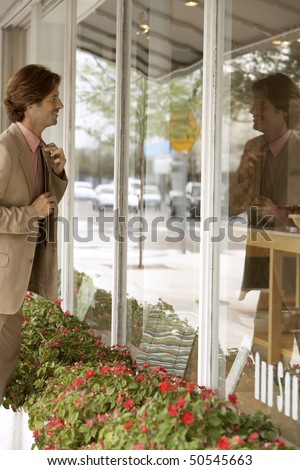 Businessman adjusting tie in shop window