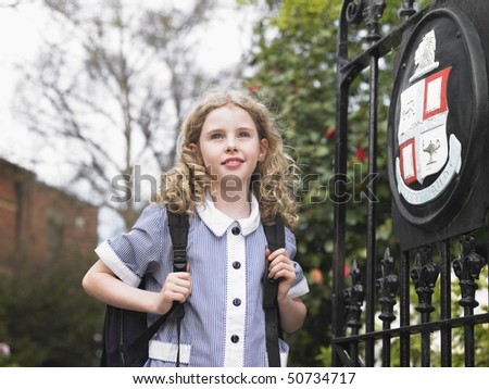 Elementary schoolgirl standing by school gate