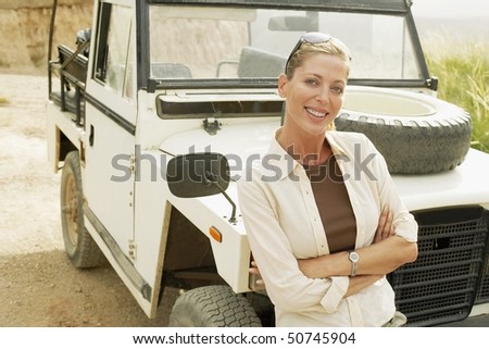 Woman standing in front of four wheel drive car in desert, portrait