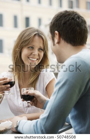 Couple sitting at outdoor cafe in Rome toasting wine glasses, head and shoulders