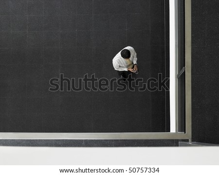 Businessman sending text message in corner of room, overhead view