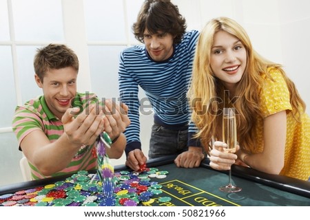 Young man with friends at roulette table playing with chips, portrait