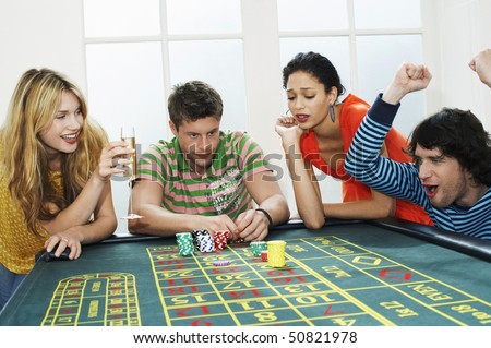 Young man winning on roulette table while friends lose