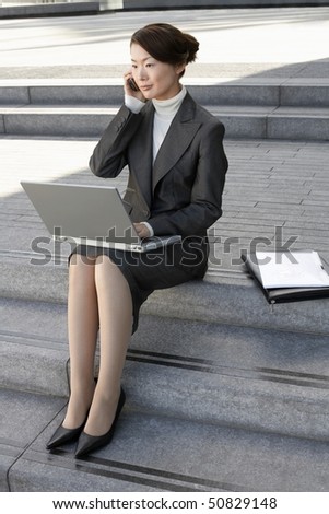 Businesswoman on outdoor Steps, Using Laptop and talking on mobile