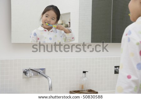 Reflection of Young Girl in pyjamas Brushing Her Teeth