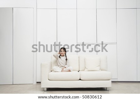 Young, barefoot Girl sitting cross-legged Sofa