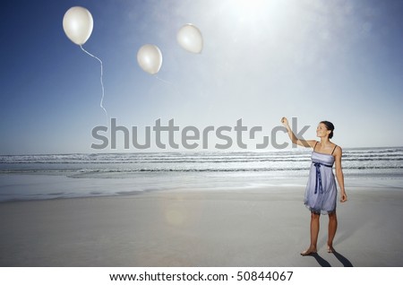 Woman letting balloons go on beach, elevated view