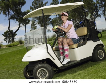 Young female golfer in sitting in cart, smiling
