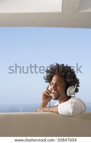 Young man listening to music through headphones, portrait