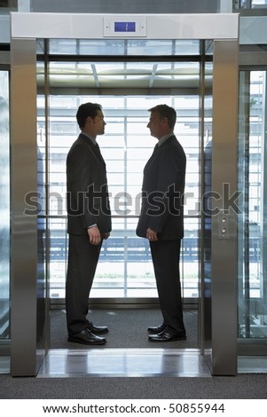 Businessmen standing face to face in elevator
