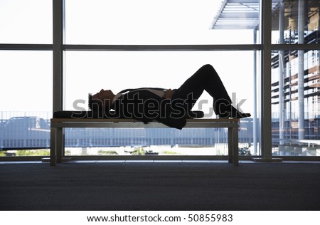 Businessman sleeping on bench in office building