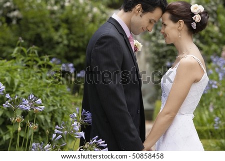 Mid adult bride and groom in garden, face to face, side view