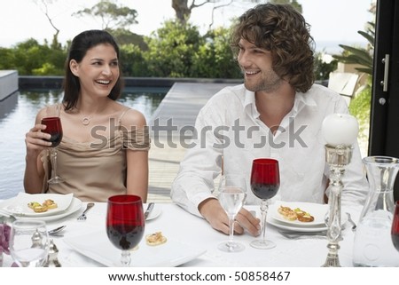 Friends sitting outside, near pool, socialising at Dinner Party
