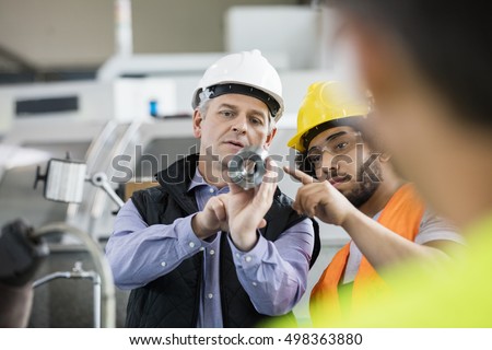 Supervisor and manual worker discussing over metal in industry