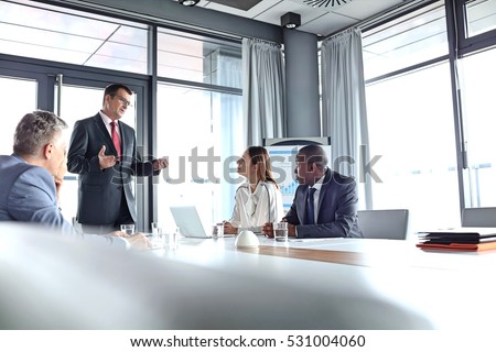 Mature businessman discussing with colleagues in board room