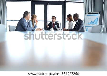 Multi-ethnic business people having discussion at table in board room
