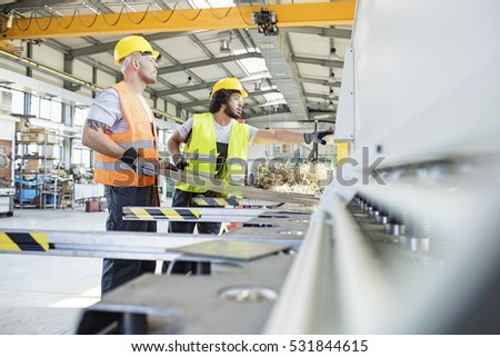 Male manual workers manufacturing sheet metal at industry