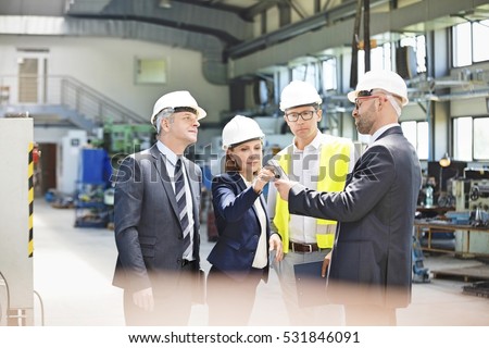 Team of business people examining machine part in metal industry