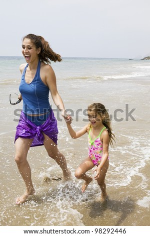 Mother and Daughter Running Through Water on Beach