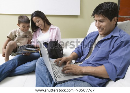 Family Using Laptop and Looking at DVD\'s on Couch
