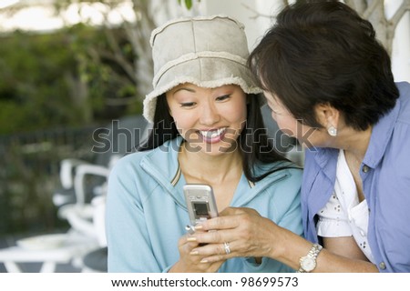 Mother and Smiling Daughter Using Cell Phone