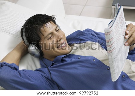 Man Listening to Music and Reading Magazine on Couch