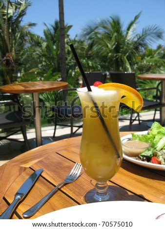 Lunch by the pool at the Atlantis Resort.  A yellowbird drink with ice, a long straw, frothy top, an orange and topped with a cherry.