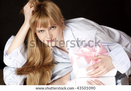beautiful woman holds a box with a pink bow on a black background