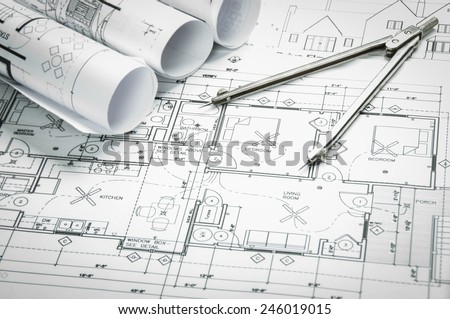 Architectural blueprints and blueprint rolls and a drawing instruments on the worktable