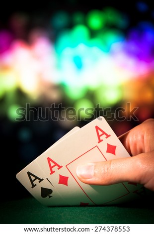 Poker hand with two aces in casino colorful background