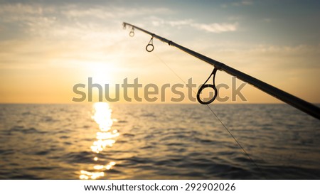 spinning rods in front of sea water sunset