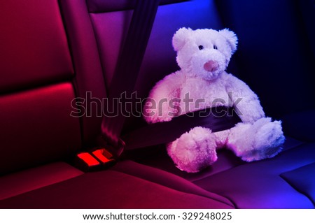 plush bear buckled on car back seat, police red blue lights
