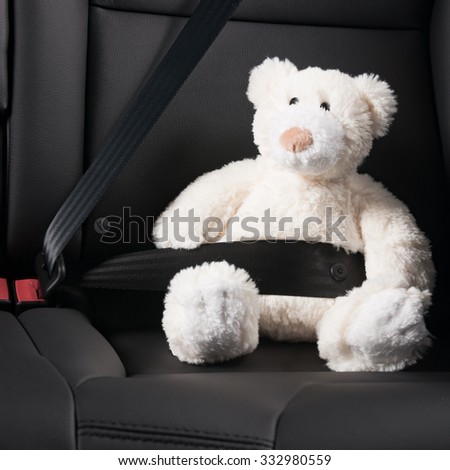 Teddy bear fastened in the back seat of a car, safety on the road
