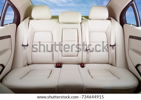 Back passenger seats in modern luxury car, frontal view, blue sky in the windows, lens flare effect