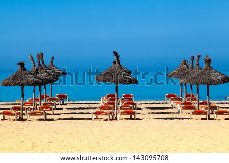 Tropical beach scenery with parasol and deck chairs.  umbrella and deck chairs
