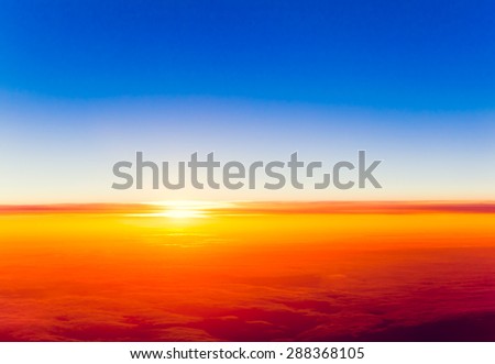 Dramatic sunset. View of sunset above clouds from airplane window