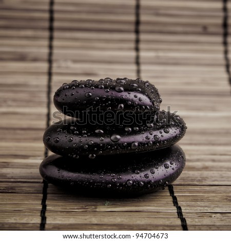 Spa Stones. black shiny zen stones with water drops over black background