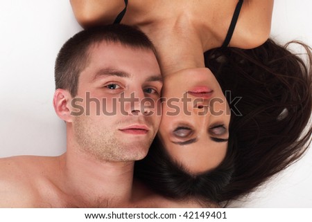 Young couple in love lying down in white background (woman covered her eyes)