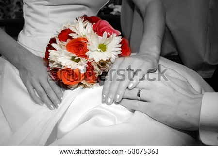 Colorful bouquet of flowers against black and white with wedding rings.
