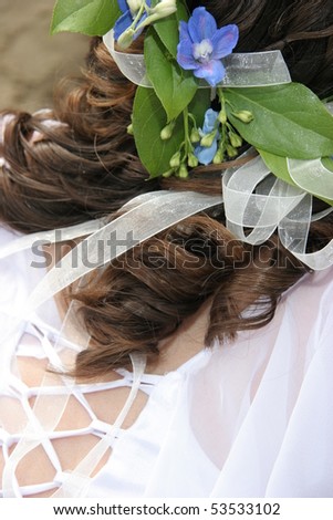 Blue flowers in a brides hair with back of dress.